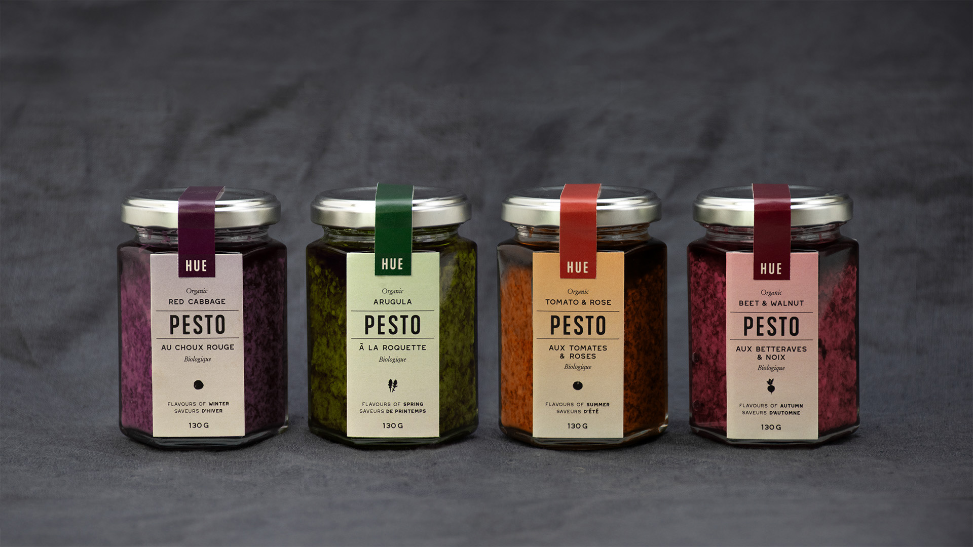 four jars in a row, containing four differently coloured pestos